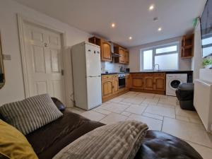 a kitchen with a couch and a white refrigerator at Nice Living Serviced Accommodations 8 (Entire 2 Ensuite Bedroom House) in Coventry +6 photos