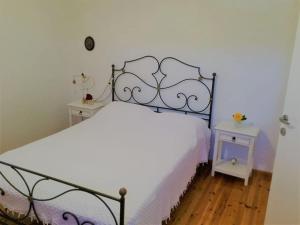 a bedroom with a white bed and two night stands at Paros spacious apartment in Prodromos Paros
