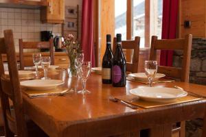 a wooden table with wine bottles and glasses on it at L'Aiglon - spacious 2-bedroom apartment with log fire in Sainte-Foy-Tarentaise