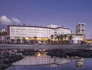 a large white building with a reflection in a body of water at Hotel Antofagasta in Antofagasta