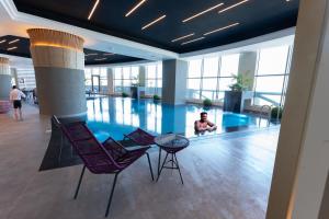 uma pessoa sentada numa piscina num edifício em Grand Hotel em Kuwait