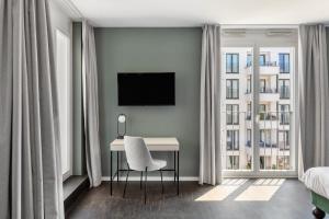a bedroom with a desk with a chair and a tv at Numa Berlin Boxer in Berlin +47 photos