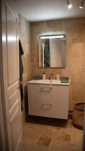La salle de bains est pourvue d'un lavabo blanc et d'un miroir. dans l'établissement Appart O moines, à Jalogny