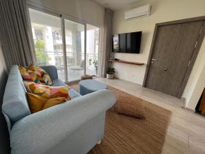 een woonkamer met een blauwe bank en een televisie bij Casa Mulata Paseo del Mar Pool & Playa in Punta Cana