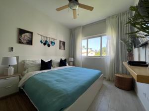 a bedroom with a bed with a blue comforter and a window at Casa Mulata Paseo del Mar Pool & Playa in Punta Cana