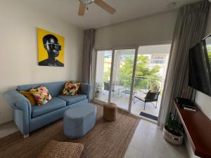 sala de estar con sofá azul y TV en Casa Mulata Paseo del Mar Pool & Playa, en Punta Cana