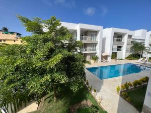 an apartment building with a swimming pool and a tree at Casa Mulata Paseo del Mar Pool & Playa in Punta Cana