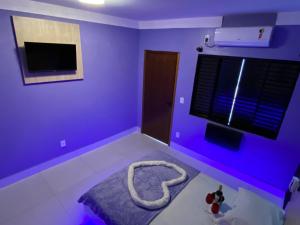 a purple room with a bed and a television at Chateau Motel Campinas in Campinas