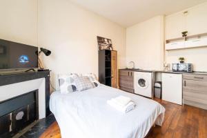 a bedroom with a white bed and a kitchen at LA BELLE PAUSE - Studio Auxerre proche parking in Auxerre
