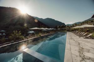 - une piscine avec des chaises et des parasols dans un complexe dans l'établissement Familien Natur Resort Moar Gut, à Grossarl