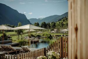 une clôture avec des chaises et des parasols à côté d'une rivière dans l'établissement Familien Natur Resort Moar Gut, à Grossarl