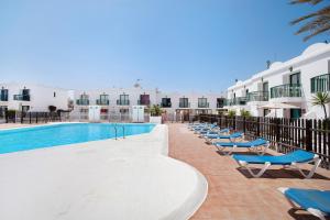 a row of lounge chairs next to a swimming pool at Piso Relax - Carpe Mundi in Corralejo
