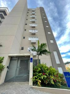 a tall building with a palm tree in front of it at Mundial Flat in Viçosa