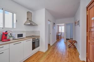 a kitchen with white cabinets and a wooden floor at Apartments Vegueta Suite in Las Palmas de Gran Canaria