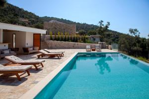 a swimming pool with chaise lounges and a house at Villa Dara and Todd in Sivota