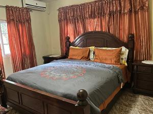 a bedroom with a large wooden bed with orange pillows at Dancehall Hostel in Kingston