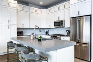 a kitchen with white cabinets and a large island with bar stools at Modern Mountain Retreat in Keetley