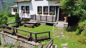 a house with a picnic bench in front of it at Авина къща in Kovachevitsa +3 photos