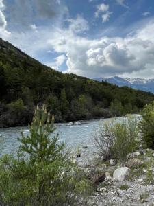 a river with trees and mountains in the background at En pleine nature avec jardin in Les Blancs