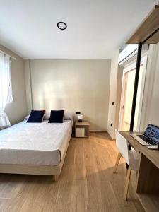 um quarto com uma cama, uma secretária e um computador portátil em Habitación bien situada, cómoda y nueva em Valência