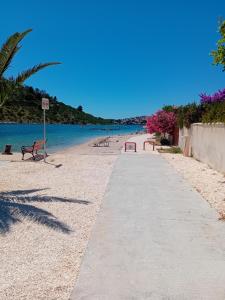 a path on a beach with benches and the water at Apartments Zora in Rogoznica