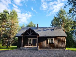 a small log cabin with chairs in front of it at Atpūtas parks Priežvanagi in Livža