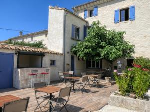 een patio met tafels en stoelen naast een gebouw bij Coeur de Provences in Saint-Didier