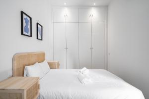 Dormitorio blanco con cama y mesa de madera en amplio duplex reformado, en Madrid