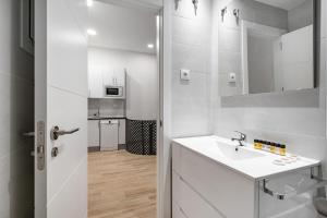 Baño blanco con lavabo y espejo en amplio duplex reformado, en Madrid