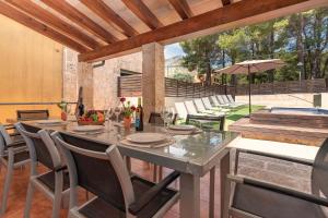 a dining table with chairs and an umbrella on a patio at Villa Nogues in Cala de Sant Vicenc