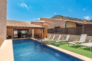 a pool with chairs and an umbrella next to a building at Villa Nogues in Cala de Sant Vicenc