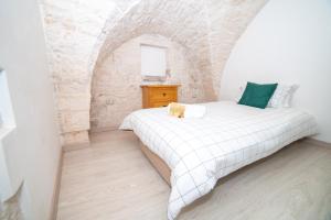 een slaapkamer met een wit bed in een stenen muur bij Terrazza Mazzini - Suite Porta Piccènne in Cisternino