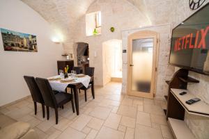 een eetkamer met een tafel en stoelen en een televisie bij Terrazza Mazzini - Suite Porta Piccènne in Cisternino