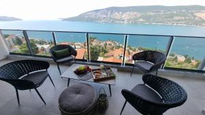 un balcón con sillas y una mesa con comida. en Novi Hills en Herceg-Novi