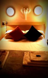 uma cama com almofadas pretas e vermelhas em Studio loft in the heart of Cape Town em Cidade do Cabo