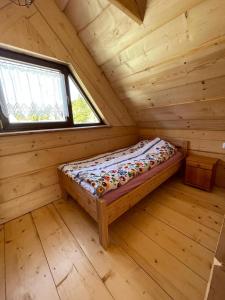 Cama en una cabaña de madera con ventana en Domek Oźna płoscyna, en Rajcza