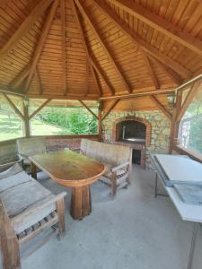 a pavilion with a table and benches and a fireplace at Vikendica Majevicka Oaza in Tuzla