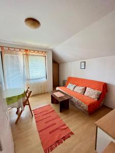 a bedroom with an orange bed and a table at Apartments and rooms Villa Mačva - Banja Koviljača in Banja Koviljača