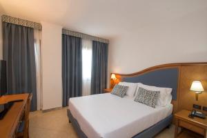 a bedroom with a large white bed and a desk at Hotel Centrale in Sabaudia