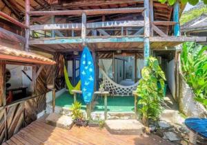 a house with a deck with a hammock and a pool at Pousada Boas Ondas in Itacaré
