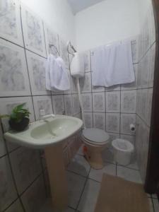 a bathroom with a sink and a toilet and towels at Pousada Boas Ondas in Itacaré