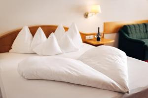 a pile of pillows on a bed in a hotel room at Hotel Bambi Am Park in Solda
