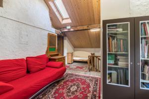 a living room with a red couch and a book shelf at Enrich Apartment in Ortisei