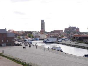 a group of people walking on a sidewalk next to a river at Ohlerich Speicher App_ 08 in Wismar