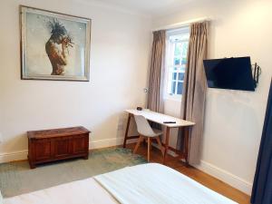 Schlafzimmer mit einem Bett, einem Schreibtisch und einem Fenster in der Unterkunft Oak Self Catering Cottage in Kapstadt
