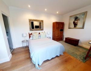 Schlafzimmer mit einem weißen Bett und einem Spiegel in der Unterkunft Oak Self Catering Cottage in Kapstadt