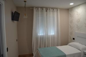 een slaapkamer met een bed en een raam met gordijnen bij Inmoinsuas Calle Greco 8 in Sarria