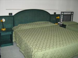 a bedroom with a large bed with a green headboard at Hotel Ristorante La Scogliera in Amantea