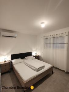 ein weißes Schlafzimmer mit einem Bett und einem Fenster in der Unterkunft La Villa Yucca Vias Plage - 300m plage et centre in Vias