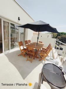 einen Tisch und Stühle mit Sonnenschirm auf dem Balkon in der Unterkunft La Villa Yucca Vias Plage - 300m plage et centre in Vias